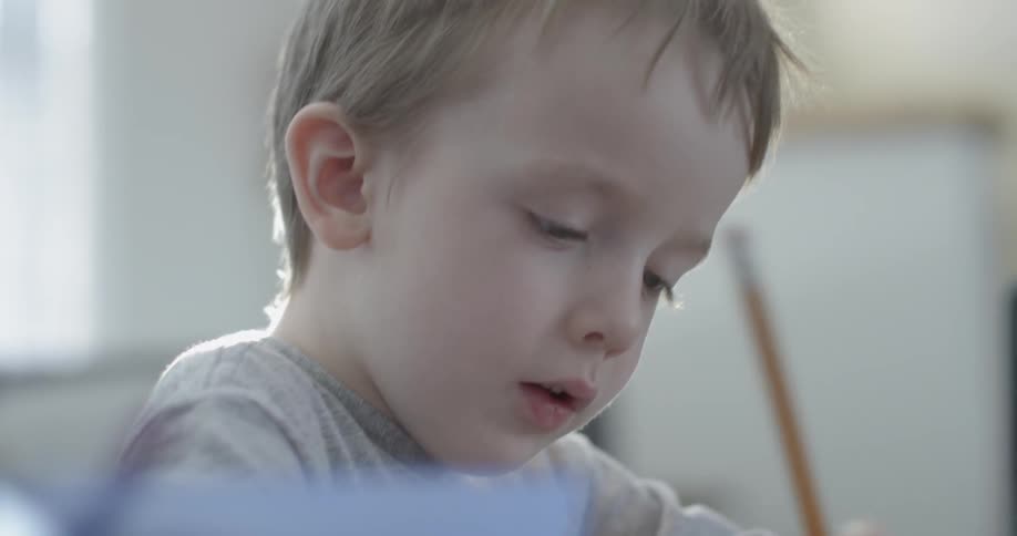 A kid is writing with a pencil