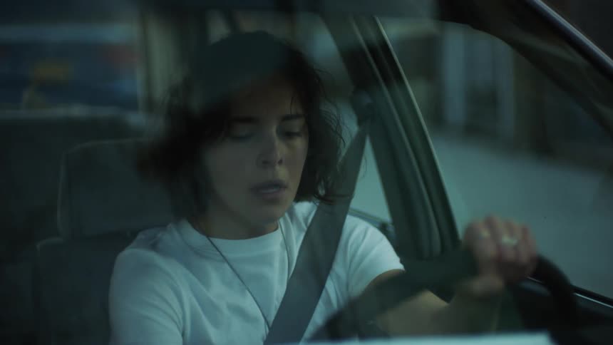 An upset woman in her car putt her hand on her head and chest then getting out of the car