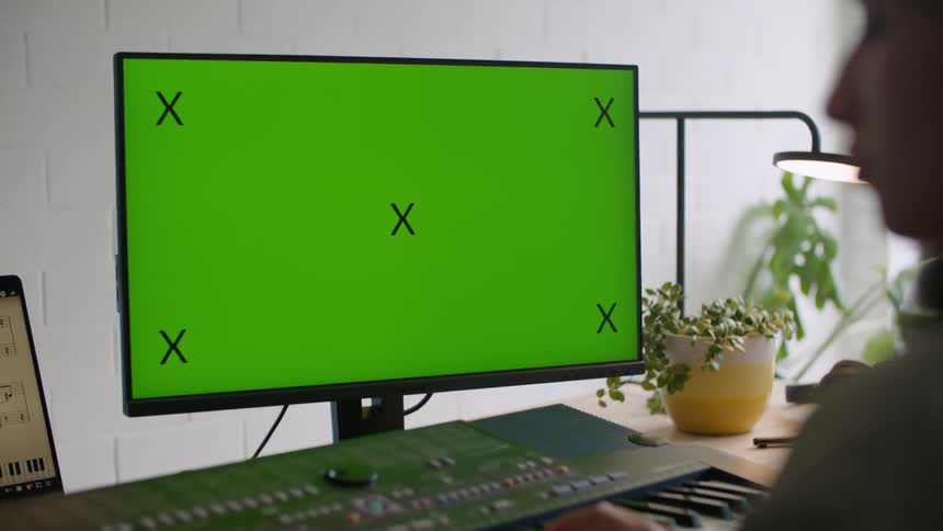 Young woman playing keyboard in front of a monitor with a green replaceable screen