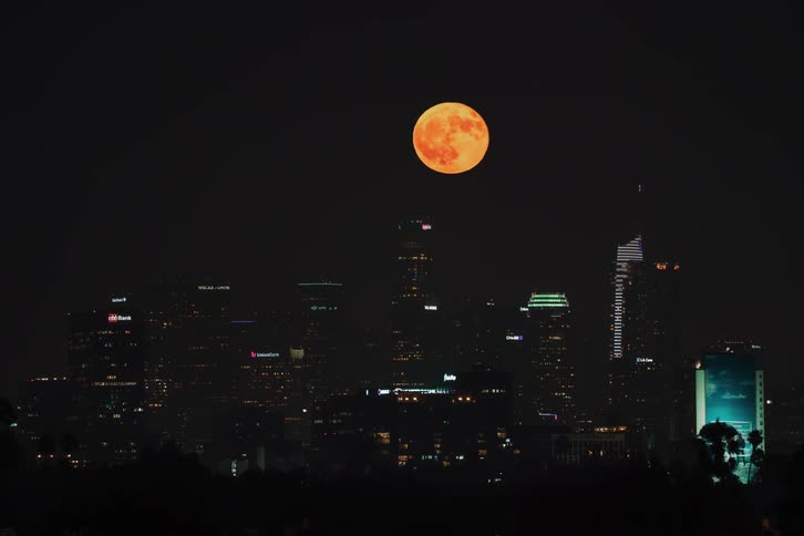 Time lapse view of the moon rising over a downtown city