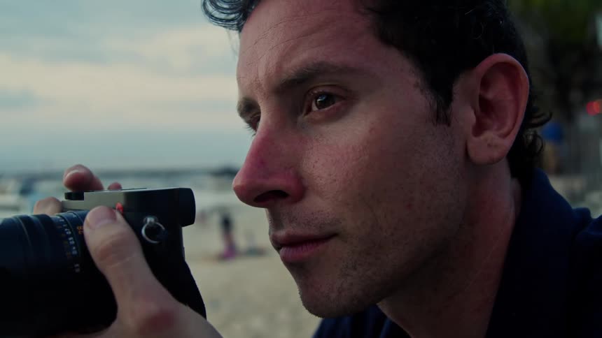 Man with black shirt takes photo with camera on the beach