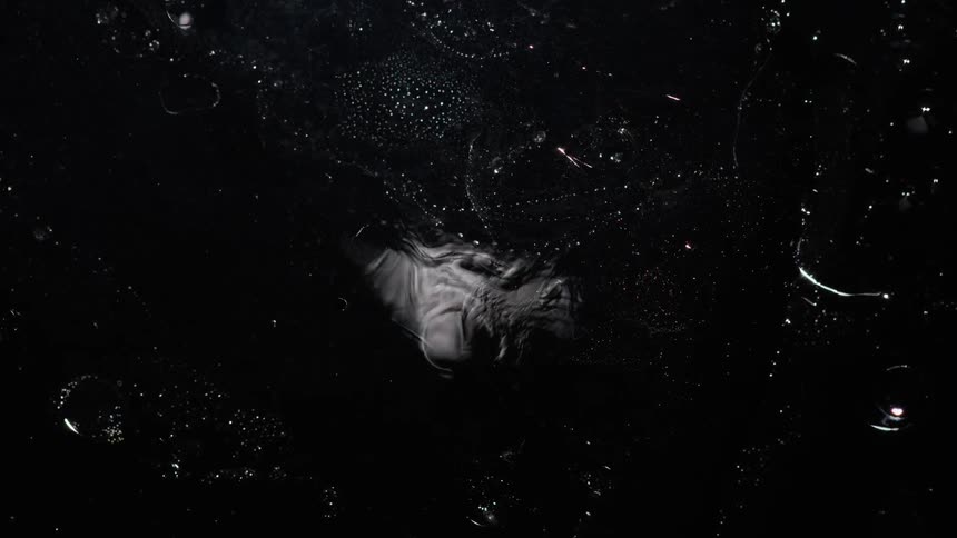 A cloudy substance moves in the darkness as lights glow like stars in space