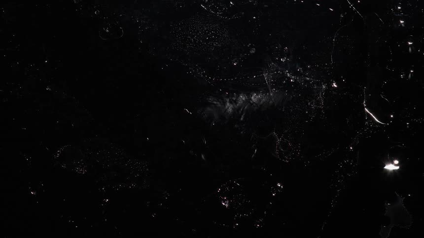 White specks floating and swirling over a deep black void