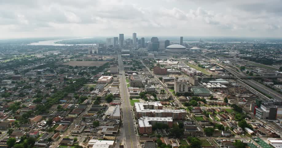 An aerial view from wide orbit showcases Mid-City streets leading to the impressive downtown skyline of New Orleans Louisiana during a cloudy day