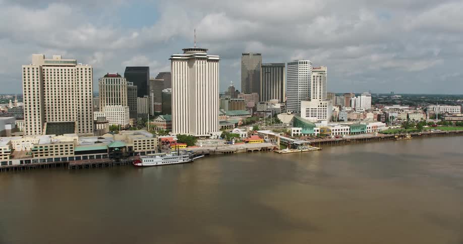 A stunning 4K aerial footage captures the Crescent City Connection and Downtown New Orleans with their high rise buildings large bridges and ships cruising in the Mississippi River on a partly cloudy day