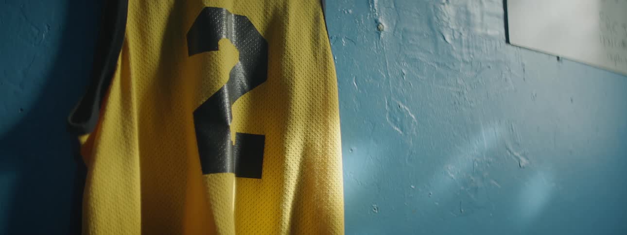 A jersey with the number 2 on it is hanging against a blue wall