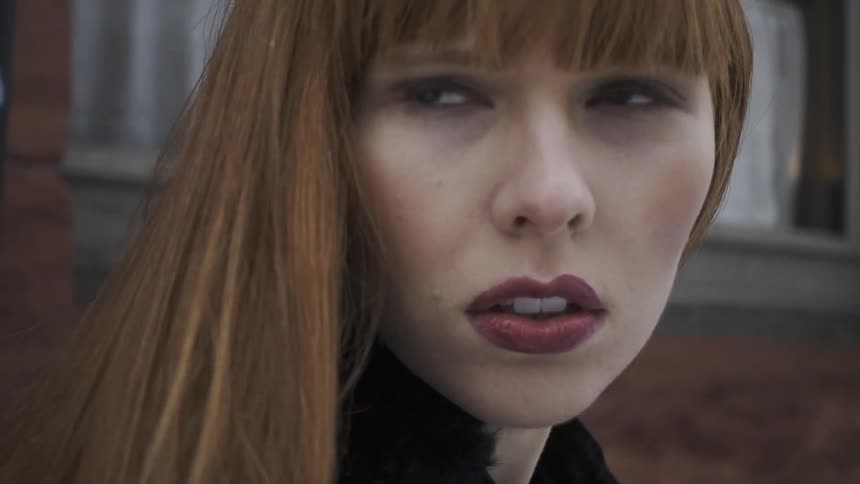 A red-haired woman looks around
