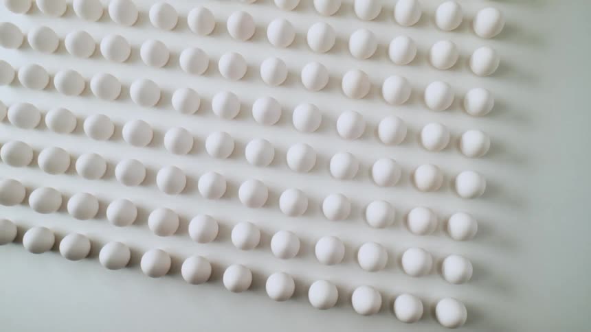 A close up of eggs and then a wide view of multiple eggs on a white surface