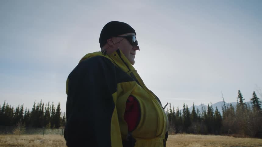 A man is smiling and hiking outdoors in the wilderness