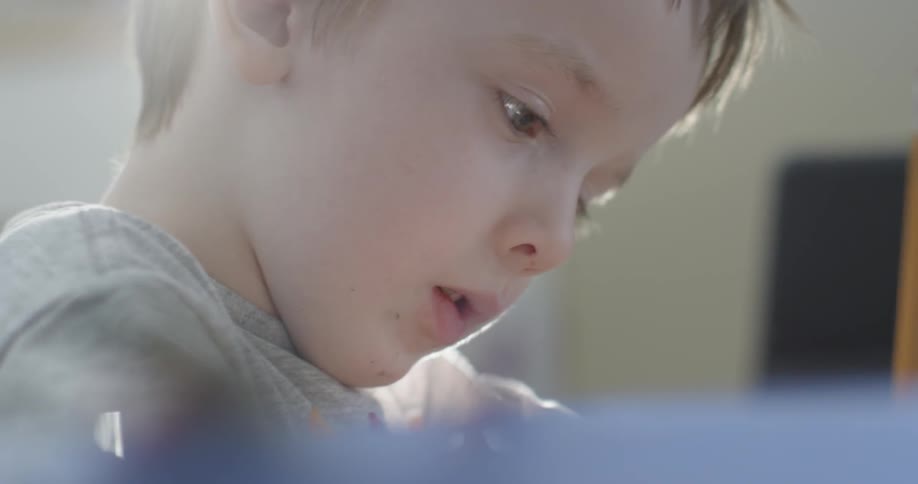 A young boy concentrating as he draws with a pencil