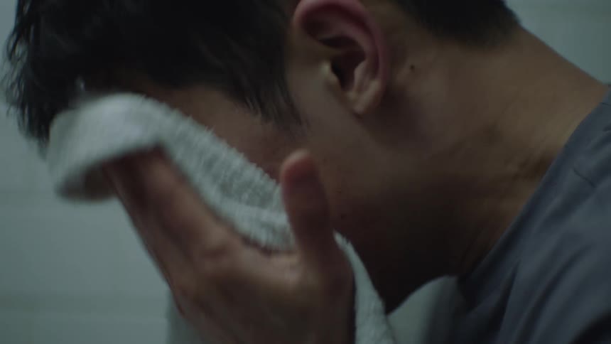 A male is drying his face off with a towel