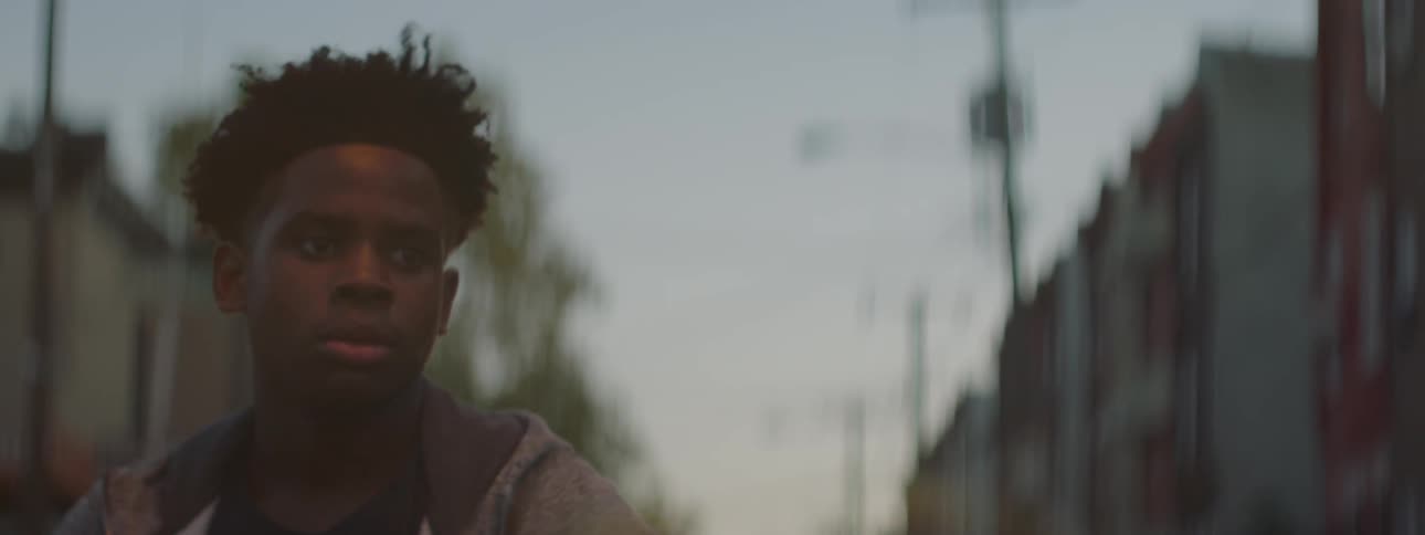 A boy is riding a bike and chewing at sunset