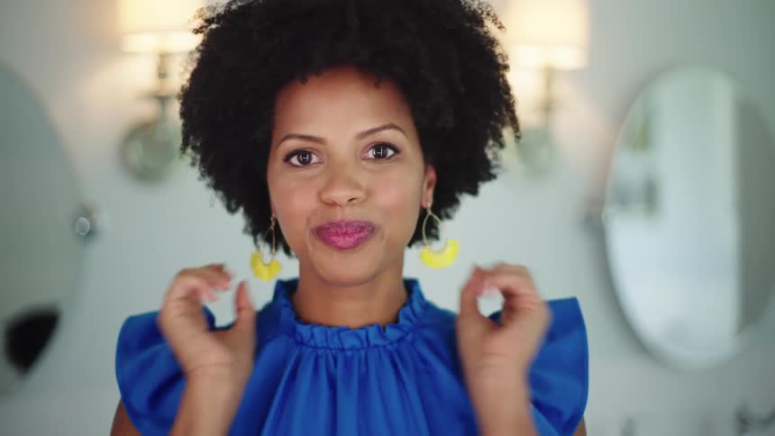 A female is smiling and putting earrings on