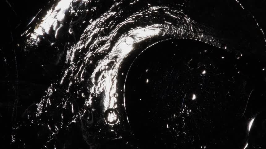 White shapes floating in waves disseminate over a deep black void