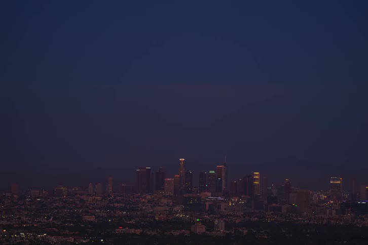 Time lapse of full moon rising in the sky behind city skyline