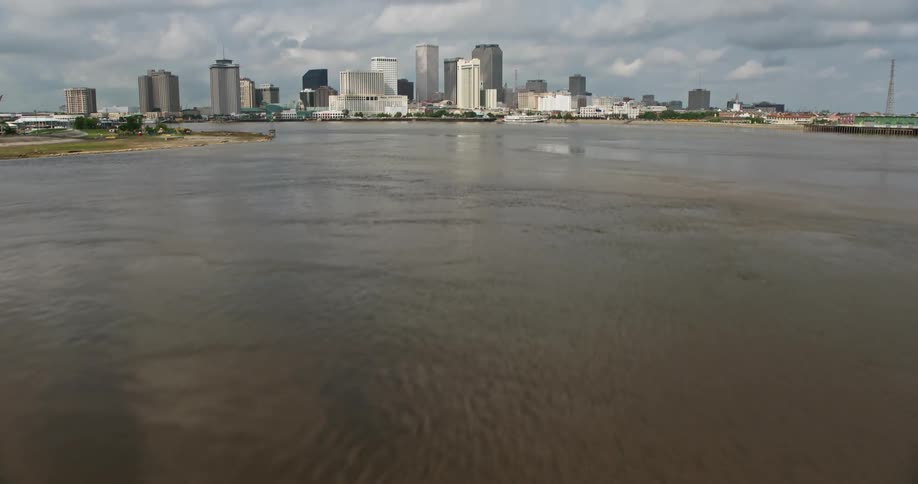 Ascending aerial view of New Orleans Downtown skyline and Mississippi River with partly cloudy skies during daytime