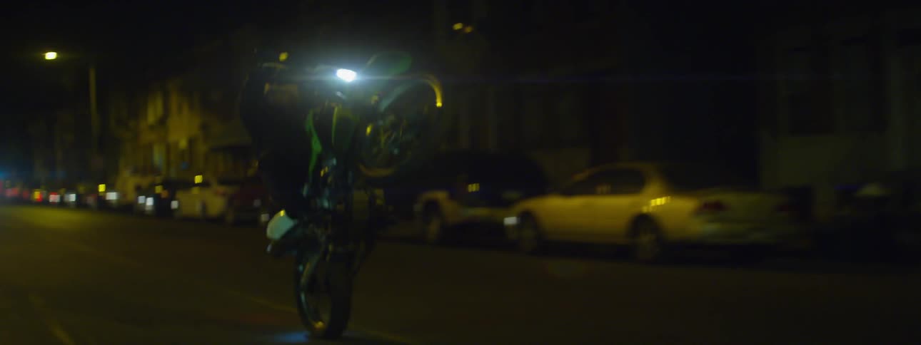 A motorcycle pops a wheelie at night