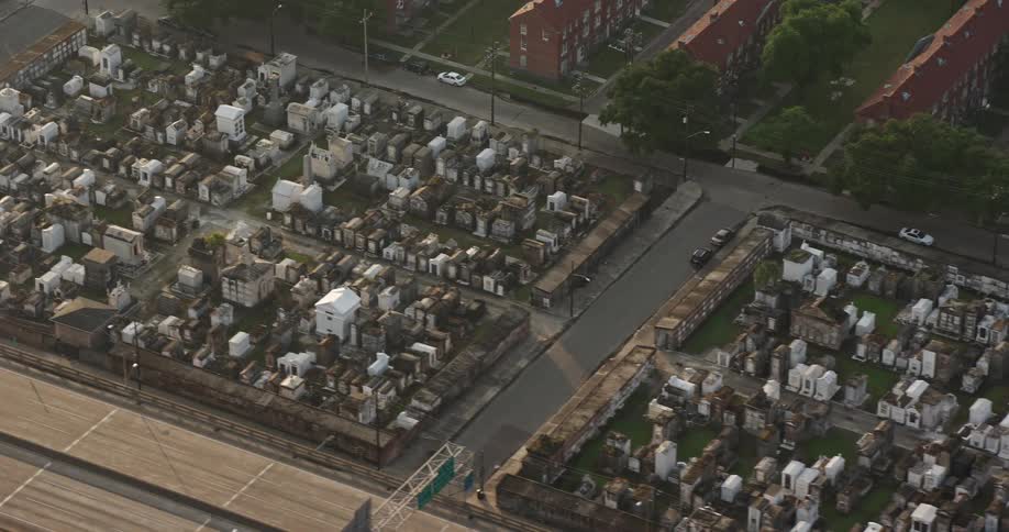 An aerial view at sunrise of two cemeteries in French Quarter New Orleans surrounded by apartment buildings and highways during a partly cloudy day in Louisiana