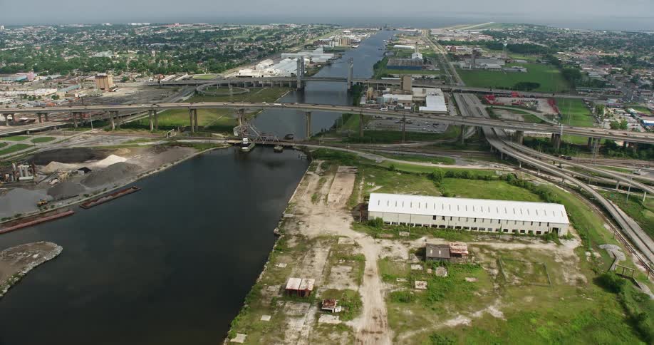 Approaching small bridges and factories in New Orleans East Louisiana an aerial view of the industrial canal and waterways during a partly cloudy day