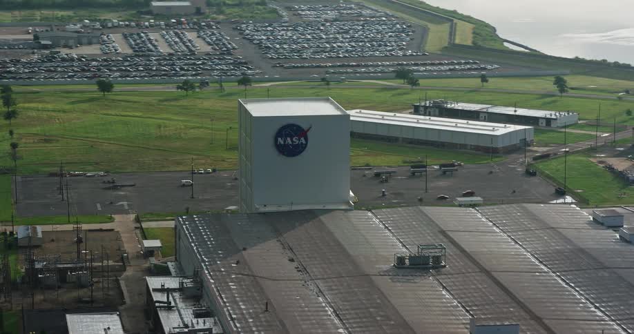 An aerial view of a factory with the NASA logo orbiting it during sunrise in New Orleans East Louisiana