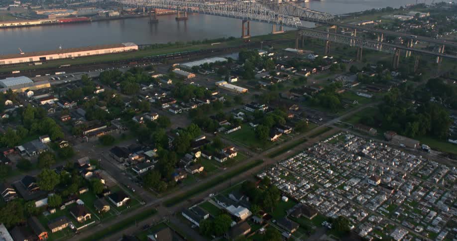 A 4K aerial footage of the sunrise over New Orleans reveals the Crescent City Connection and downtown as the camera tilts up from a cemetery