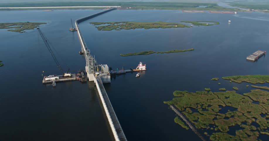An aerial pan of the surge barrier and gate orbit during sunrise in St Bernard Parish bayou Louisiana surrounded by wetlands and marsh