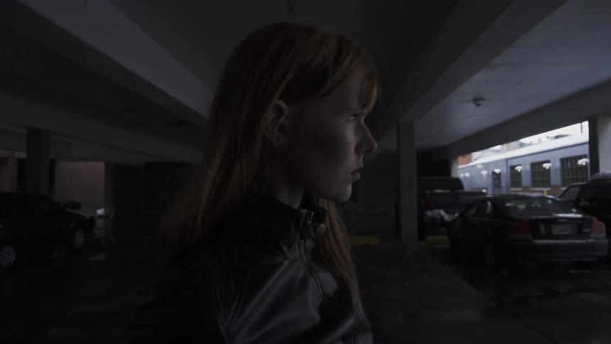 A woman is walking in a dark lot