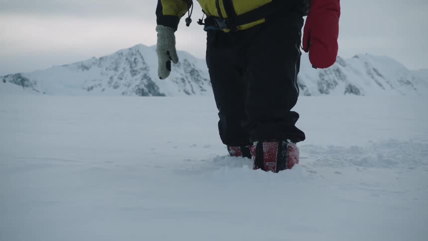 Man walking in deep snow atop a mountain top