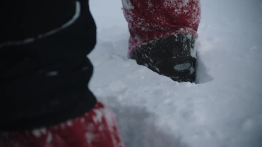 Person wearing red and black stands ankle deep in snow
