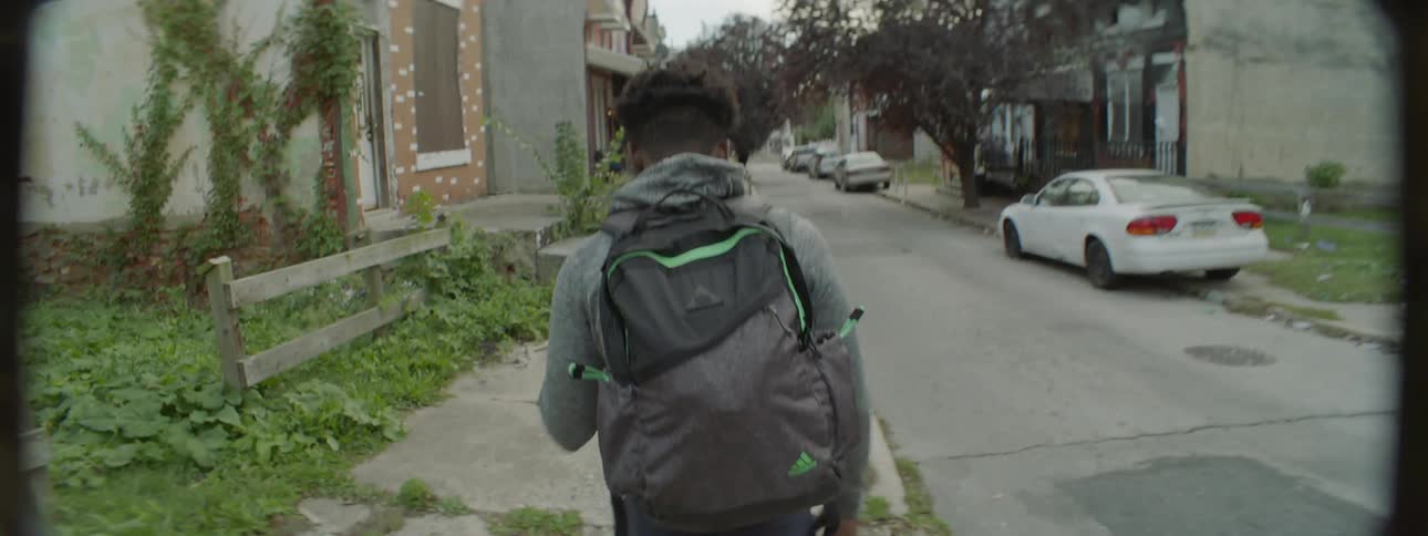 A boy is dribbling a basketball walking down a sidewalk