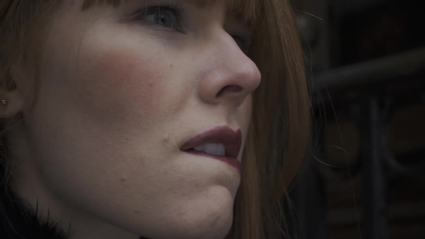 A red haired woman bites her lip
