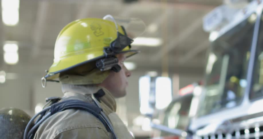 A fireman is standing in front of a fire truck