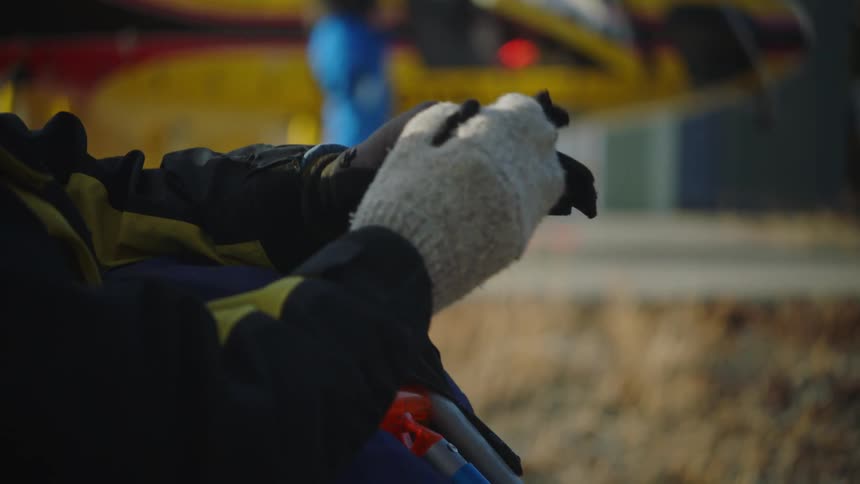 A person wearing a heavy coat in an outdoor setting puts a pair of gloves on his hands