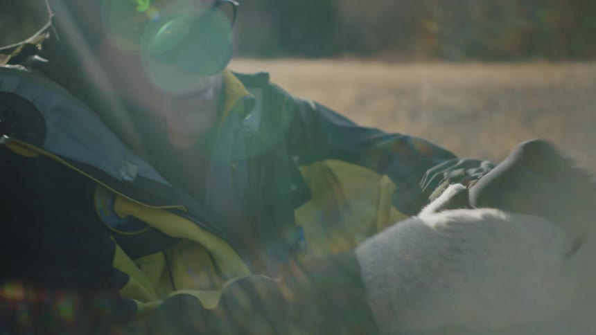 A close up of a man sitting outside putting gloves on