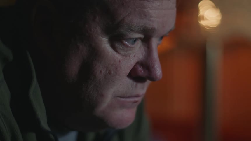 Close up of the face of a man sitting on a room lost in thought