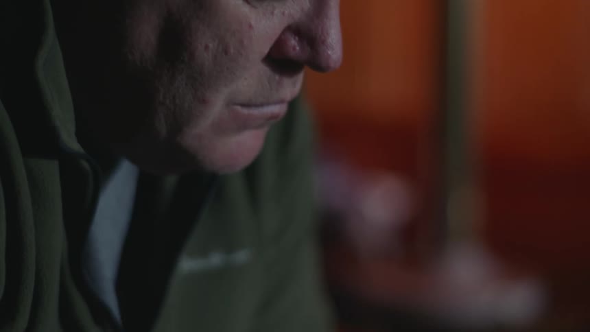Close up of a man sitting on a room at home lost in thought while rubbing his fingers