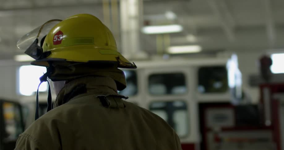 A fireman walks through a garage towards a firetruck