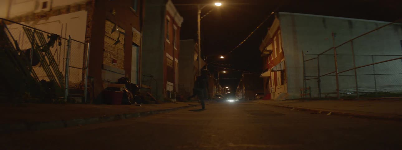 Two men run across a street at night