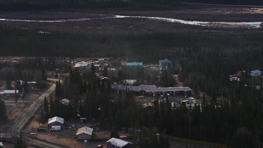 A neighborhood is shown that is not in good shape with a few houses and dirt roads