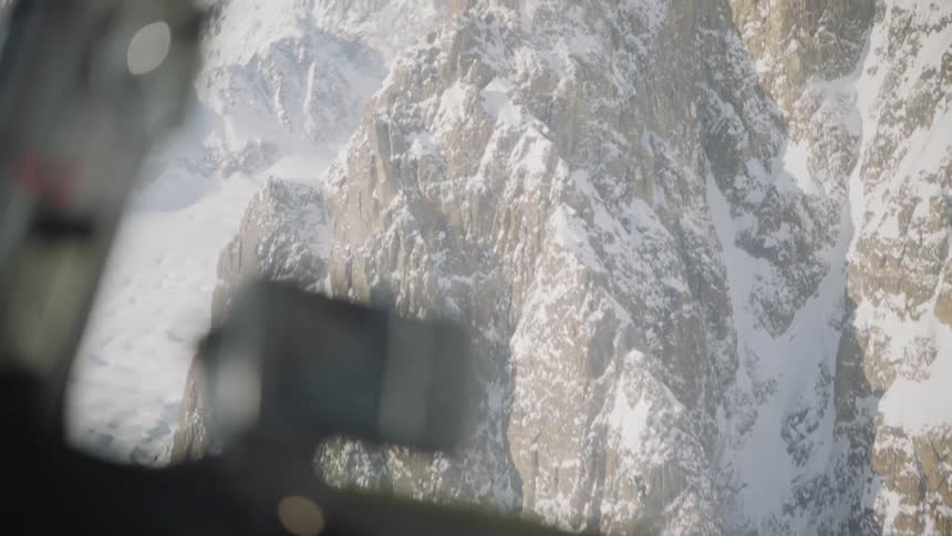 A snow covered mountain peak from inside of a helicopter