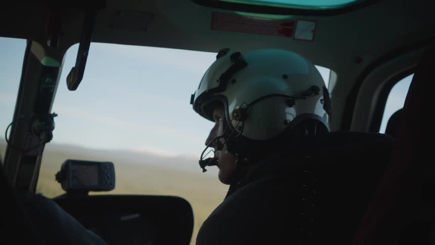 A pilot is flying an aircraft over land and there are mountains in the distance