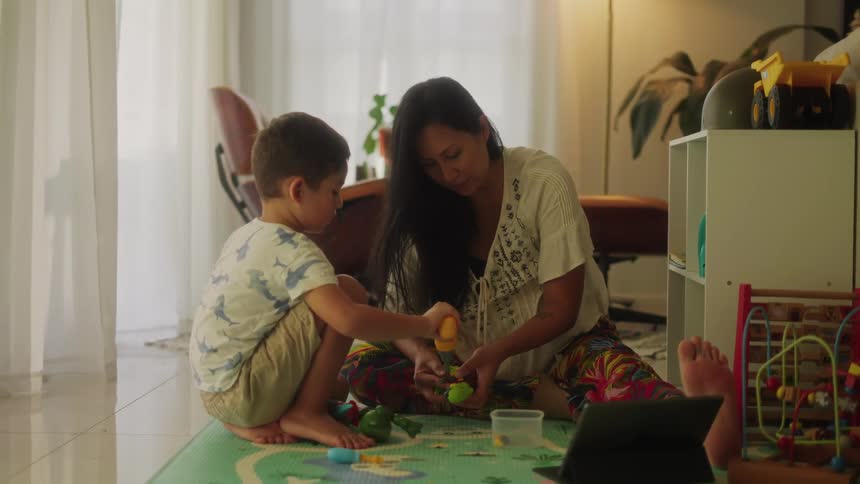 A mother and son sit on the floor playing as they put pieces together