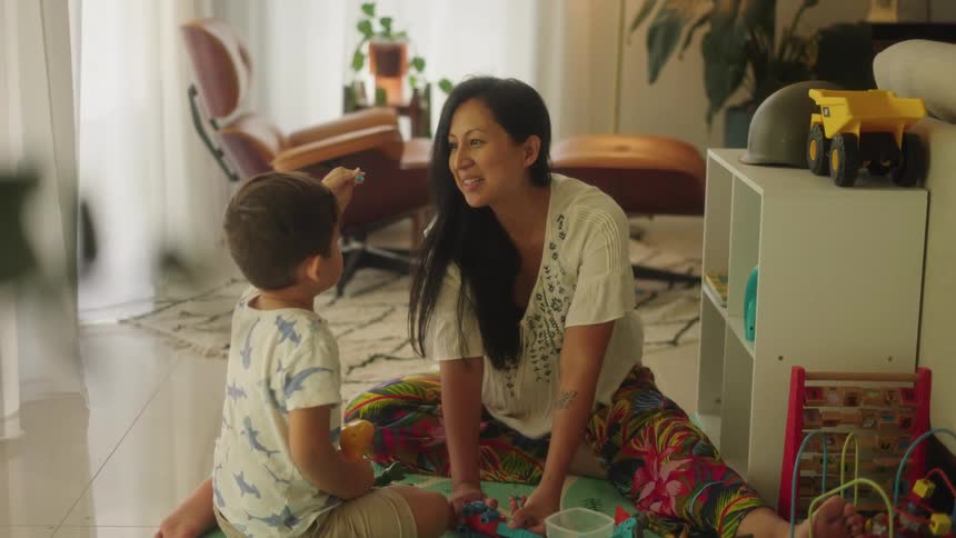 Mother and son sitting on the floor playing with toys indoors