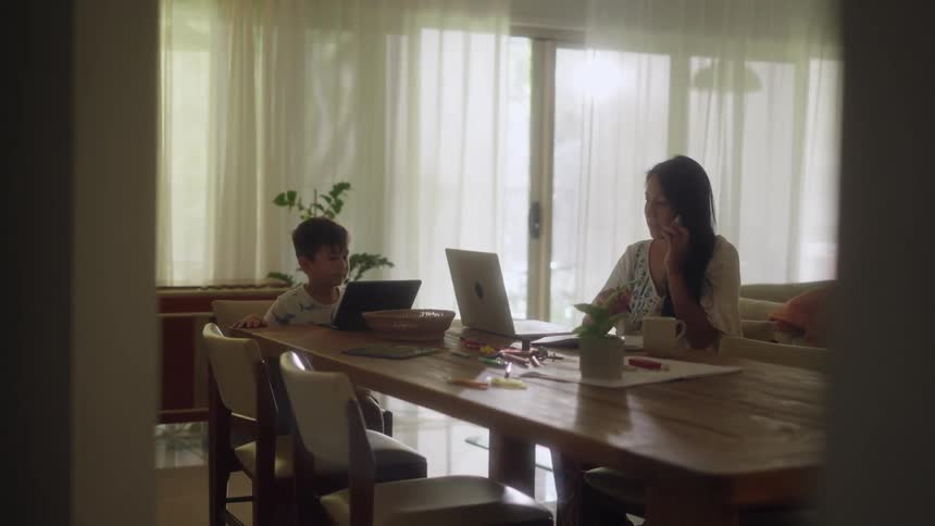 A woman and child sit at a table with laptop computers