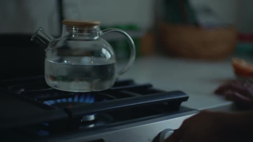 Womans hand turning on gas stove in the kitchen