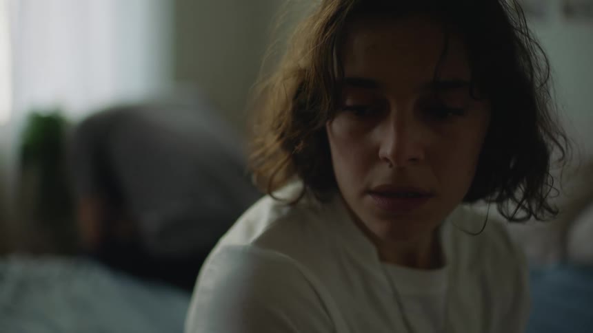 A woman is sitting on her bed during the day time