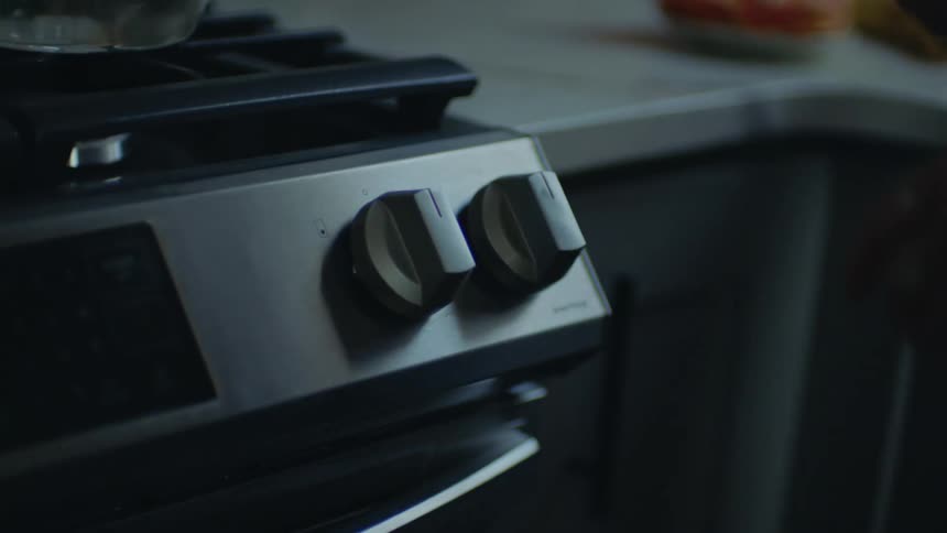 Close up of the hand of a person turning off a stove at home