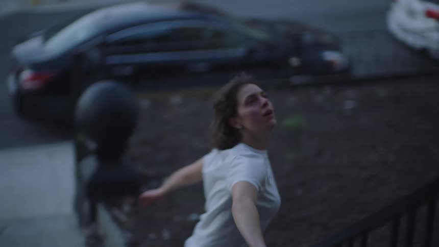 A woman running down stairs going outside and looking up at her house nervously before running into the street frantic