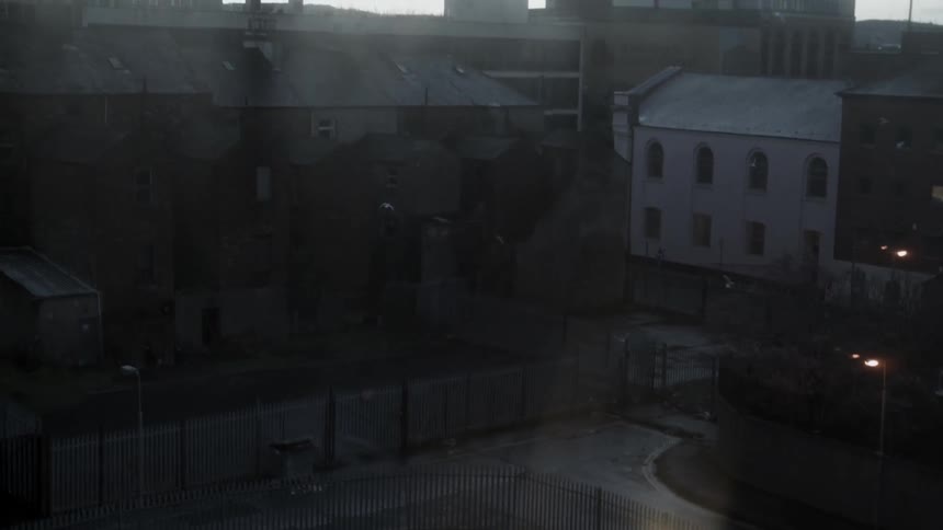 A parking lot and buildings are seen through a window