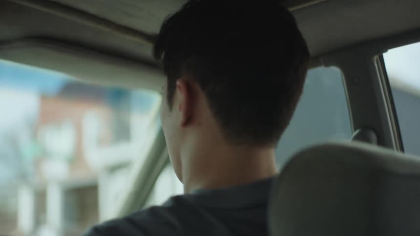 A man gets out of a moving car as it drives through a neighborhood